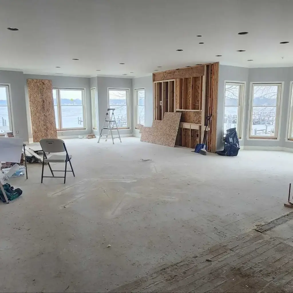 Lake Macatawa home interior renovation in progress with exposed wall framing, large windows, and an open living space.