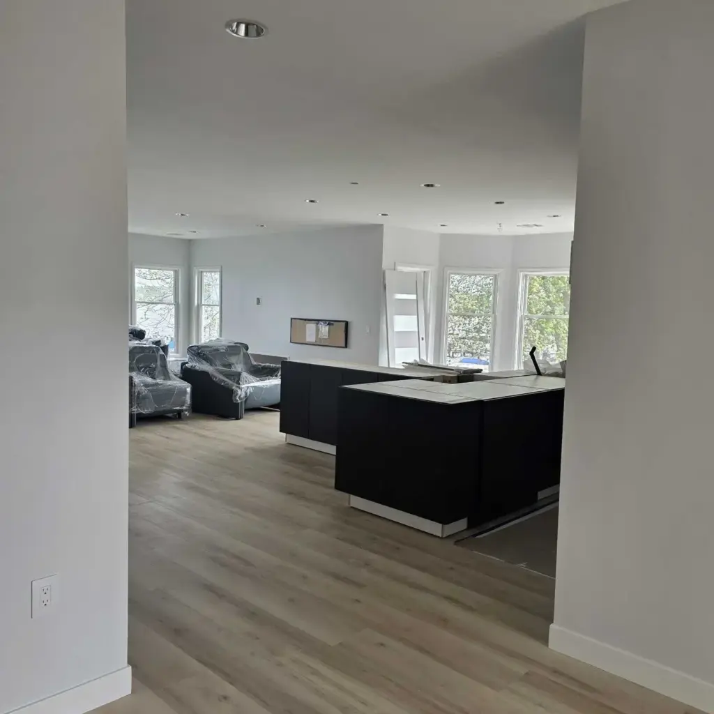 Lake Macatawa open-concept kitchen and living area featuring a modern black island, light wood flooring, large windows, and updated interior finishes.