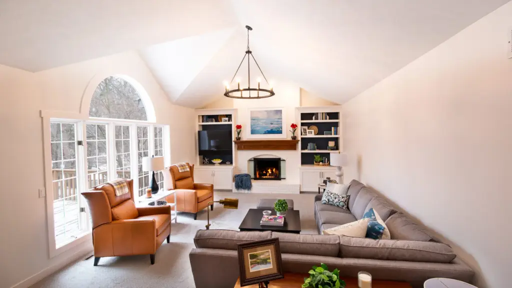 Custom home living room with vaulted ceiling, fireplace, built-in shelving, and large windows