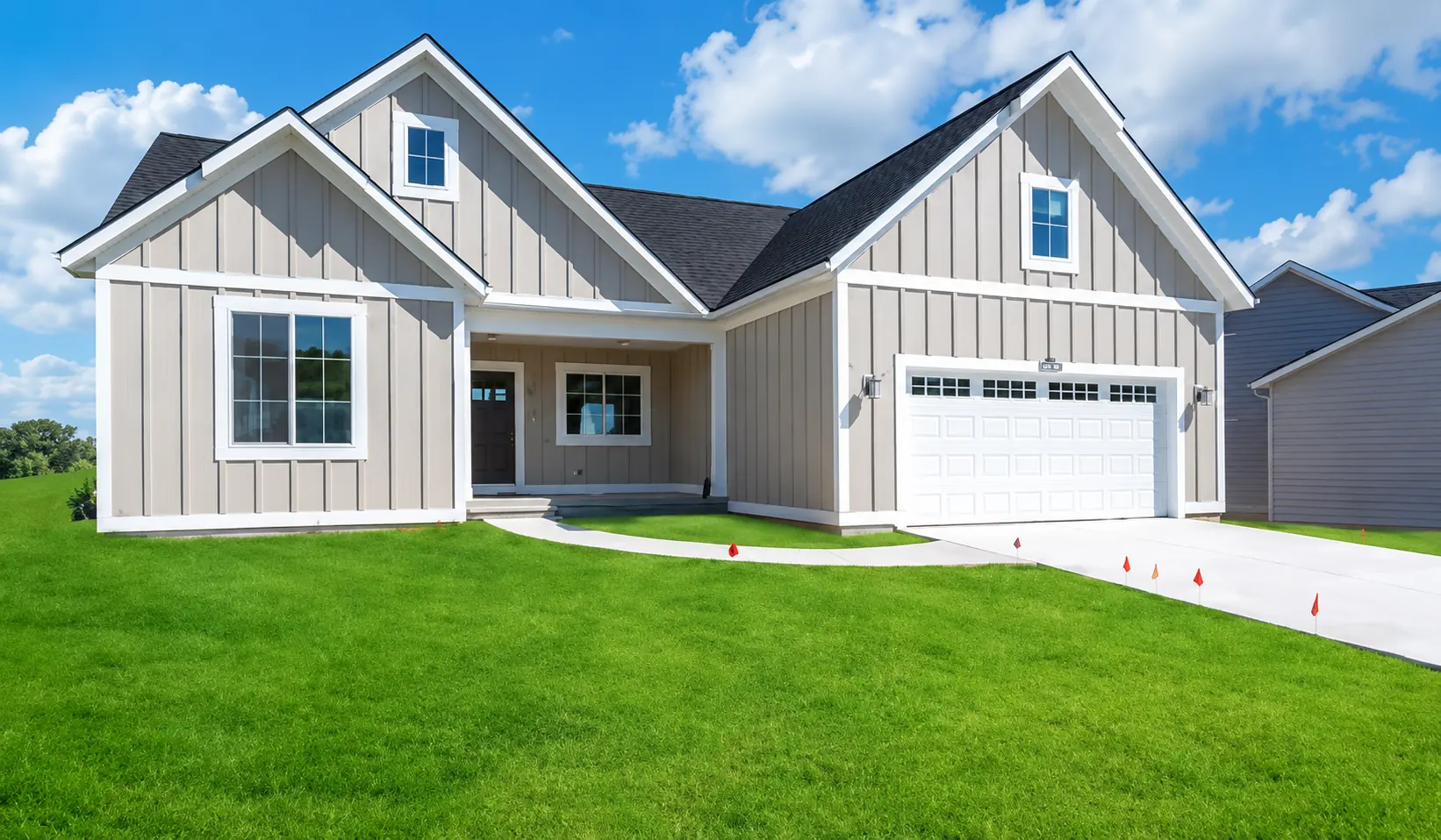 Gray custom home with white trim, attached garage, and green front lawn