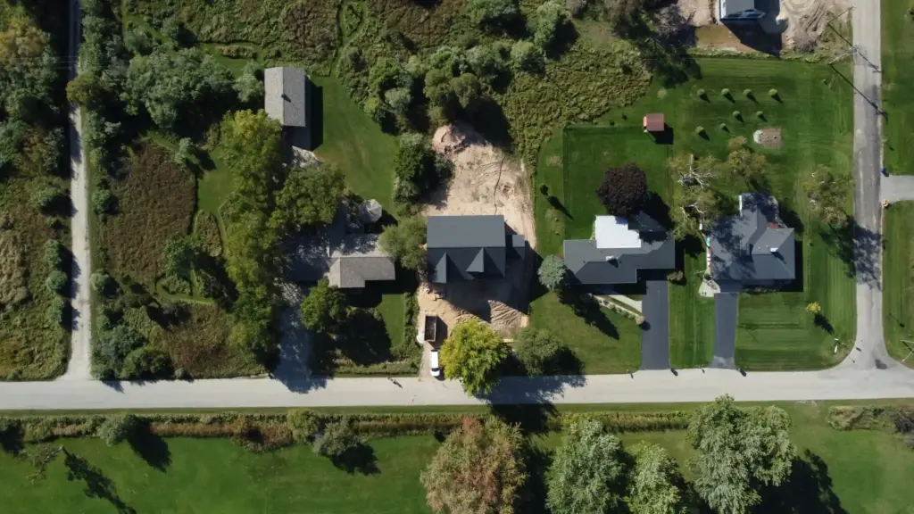 Aerial view of homes and wooded properties near a rural road in West Michigan