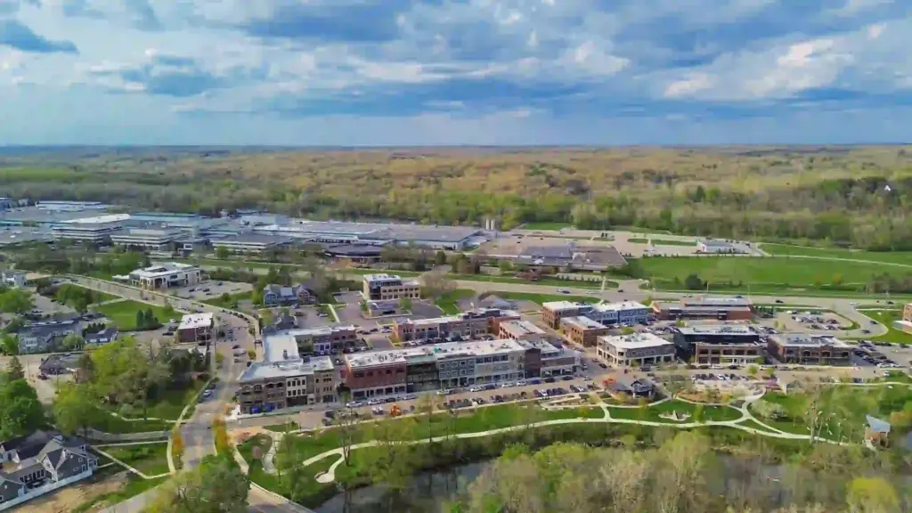 Aerial view of downtown Ada, Michigan, with local businesses, parks, roads, and surrounding wooded areas