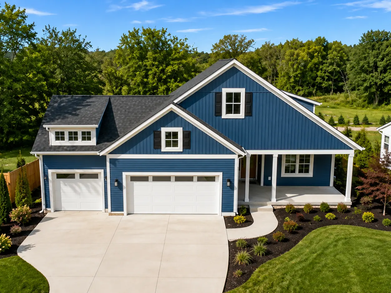 Blue custom home with white trim, covered front porch, three-car garage, and landscaped yard in West Michigan