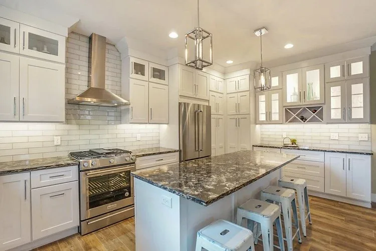 White custom kitchen with granite island and stainless steel appliances in West Michigan.