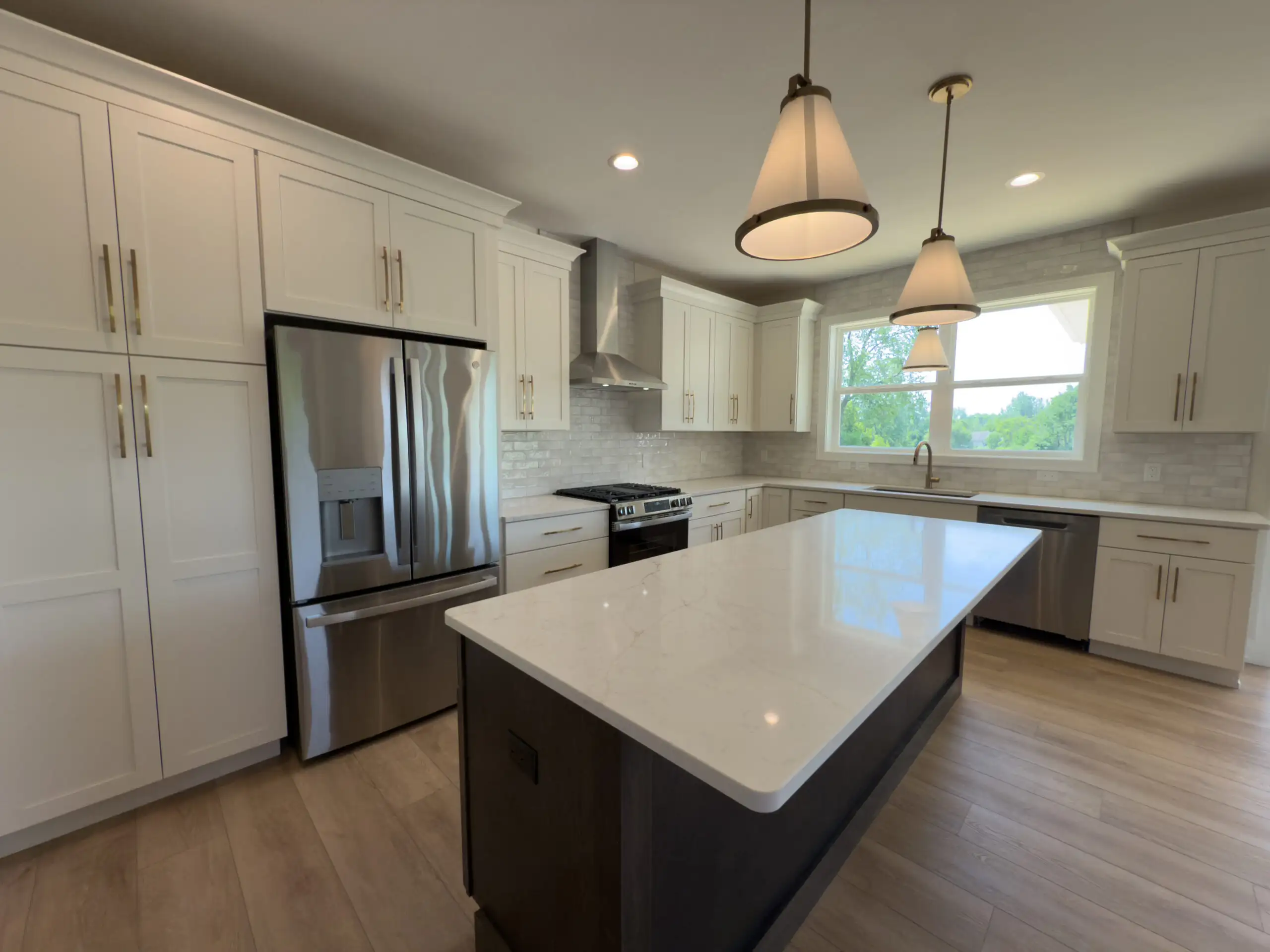 Modern custom kitchen with white cabinetry, quartz island, stainless steel appliances, and pendant lighting