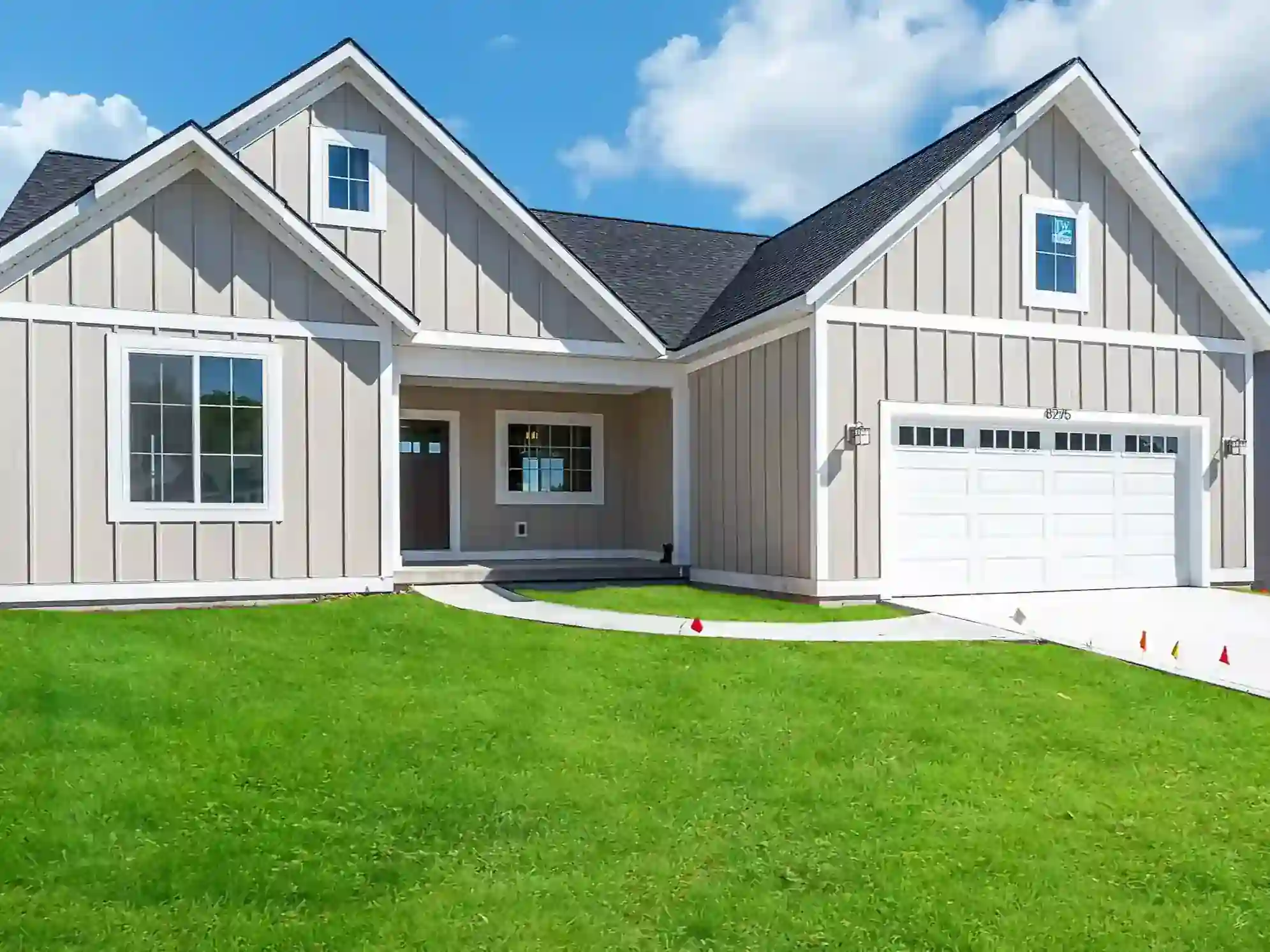 Gray board-and-batten custom home with white trim and attached garage in West Michigan