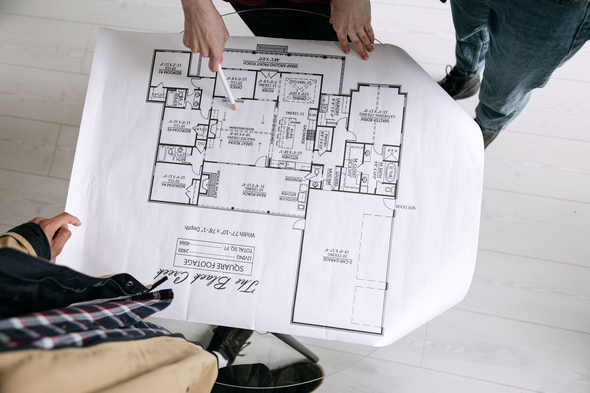Two architects examining a detailed floor plan blueprint on a table indoors.