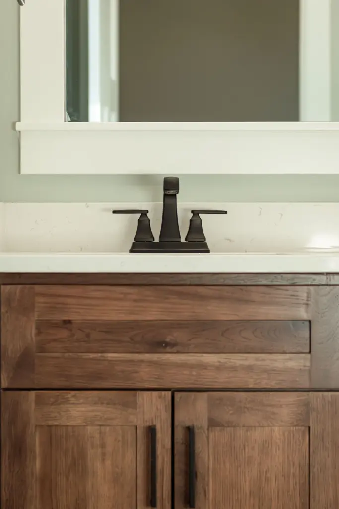 Waterfront home bathroom with wood vanity, white counter, and matte black faucet