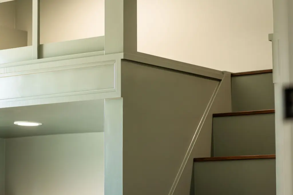 Built-in bunk bed stairs with wood treads and green painted millwork