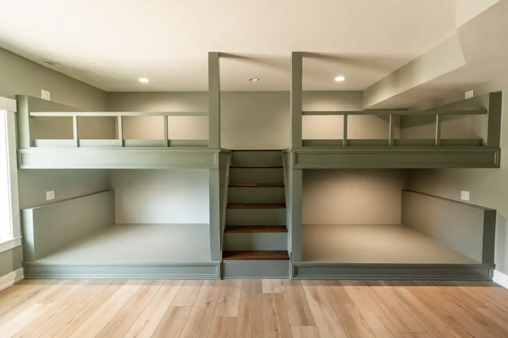 Waterfront home bunk room with four built-in beds and central wood stairs