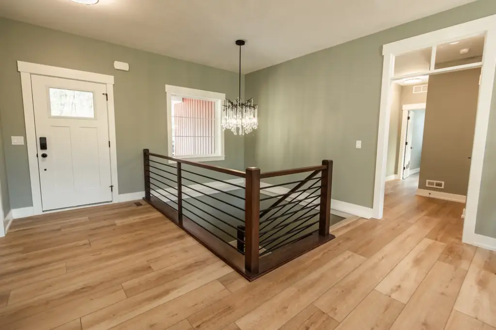 Waterfront home entry with wood floors, cable railing, and crystal chandelier