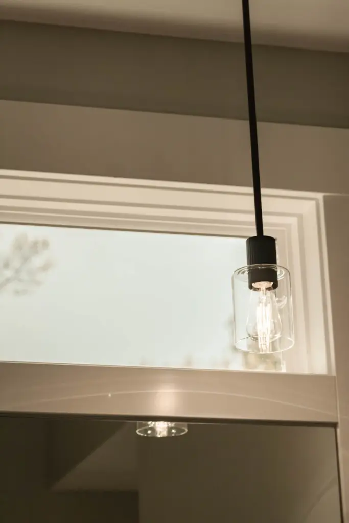 Clear glass pendant light beside a window in a waterfront home