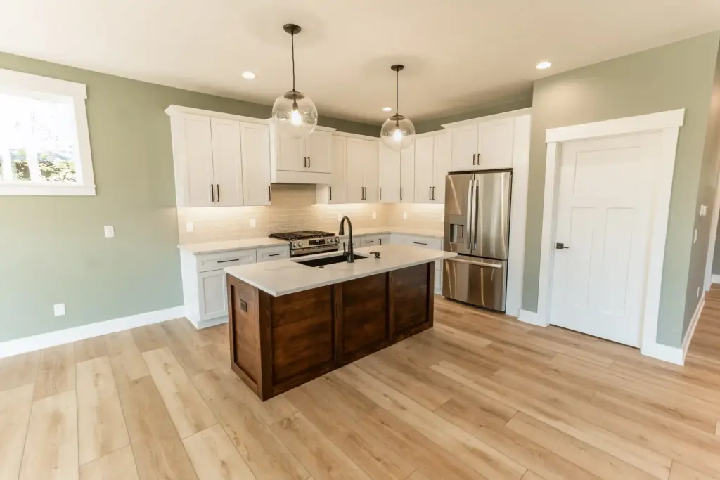 Waterfront home kitchen with white cabinets, wood island, and glass pendant lights