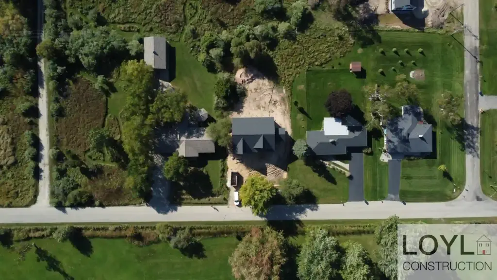 Overhead aerial of a waterfront-area home site, road, lawns, and neighboring houses