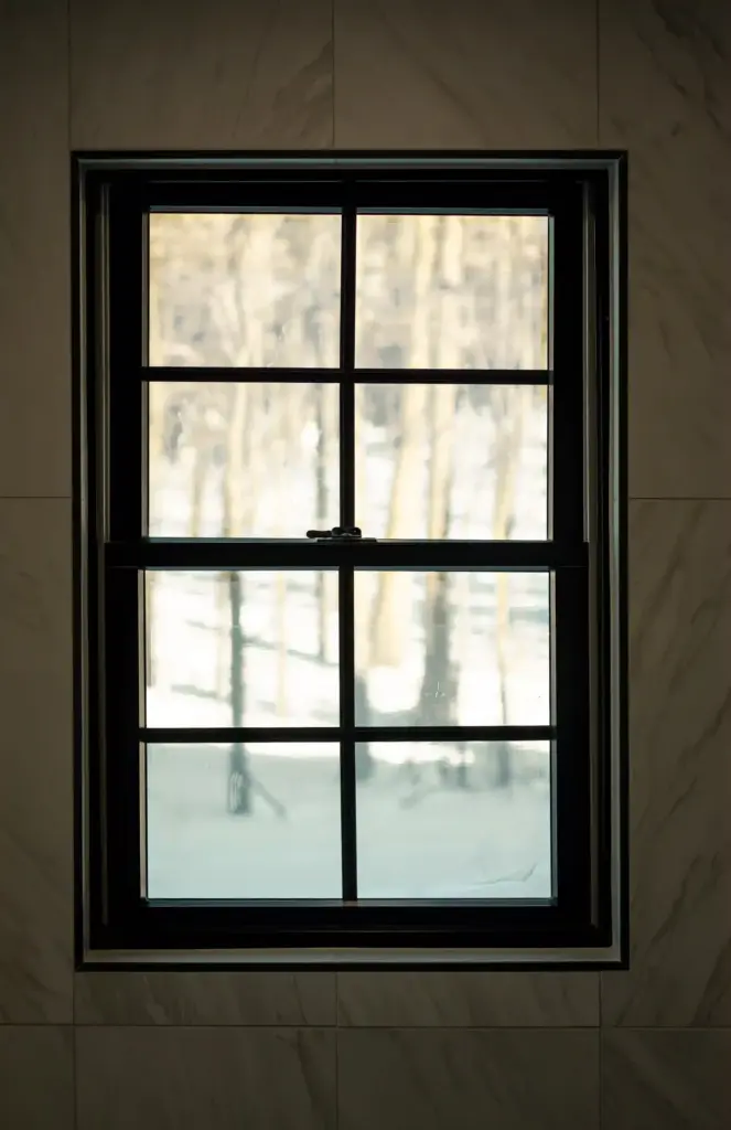 Black-trimmed bathroom window surrounded by marble-look wall tile
