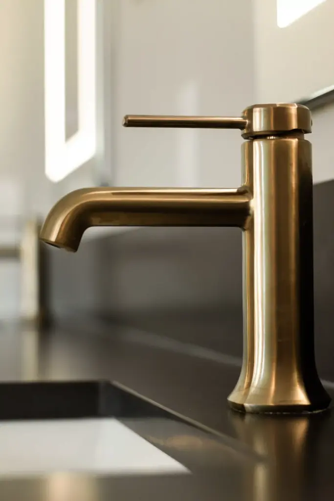 Brushed brass faucet on a dark countertop in a renovated bathroom