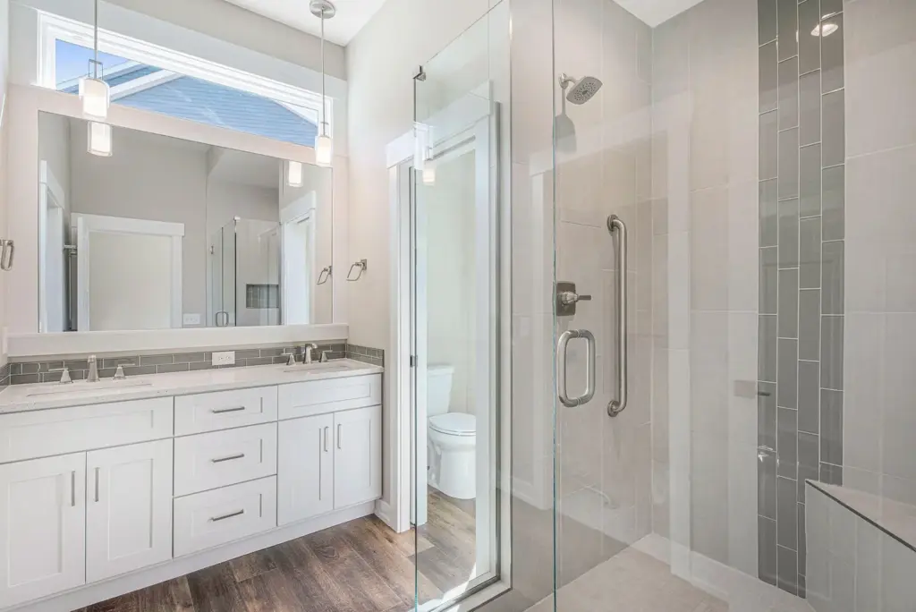 Custom home bathroom with double vanity, large mirror, and glass walk-in shower
