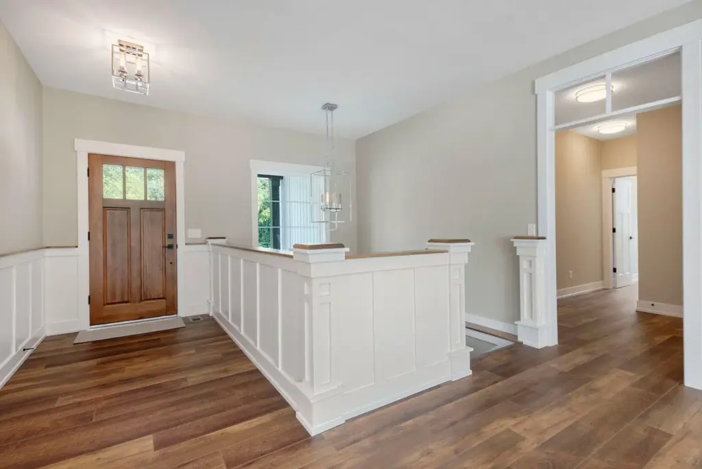 Custom home entry with wood front door, white millwork, and open stair railing