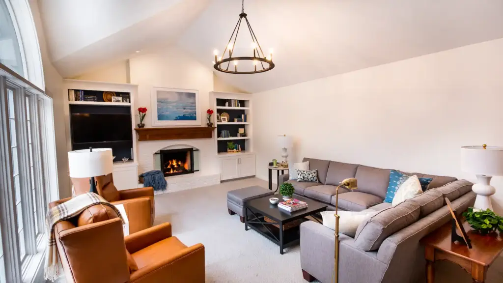 Custom home living room with fireplace, built-in shelves, and large arched windows