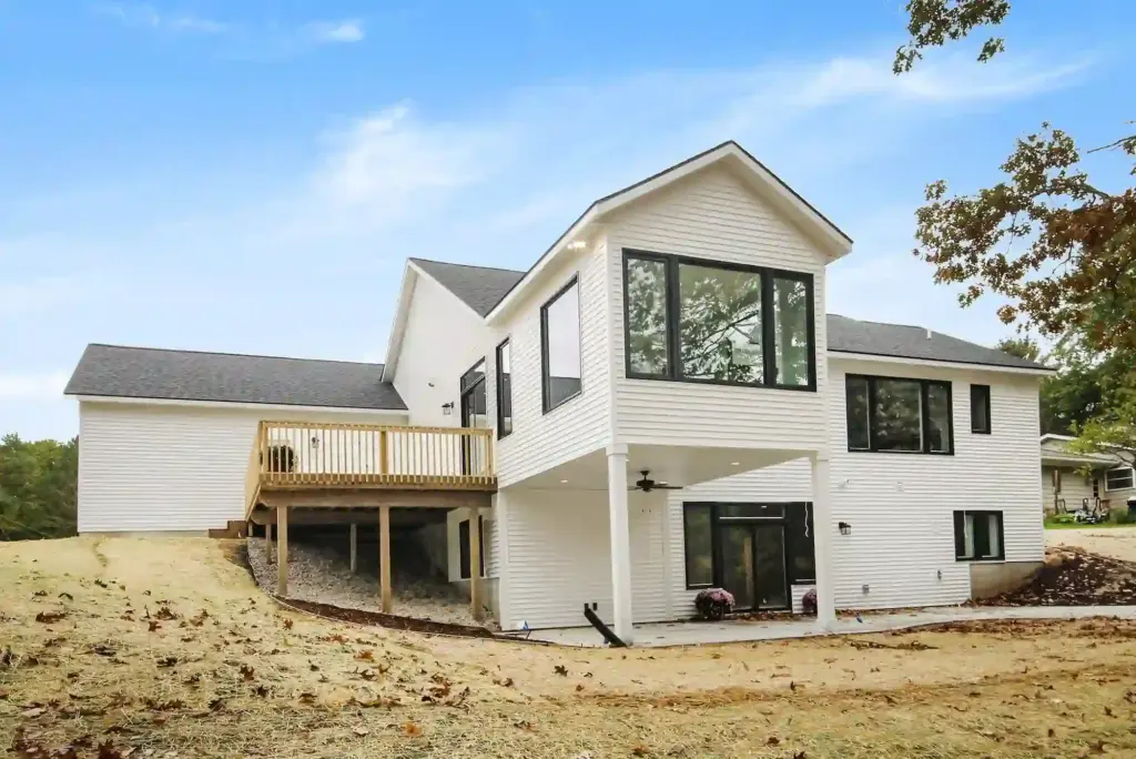 Rear exterior of a white custom home with elevated deck and large black-framed windows