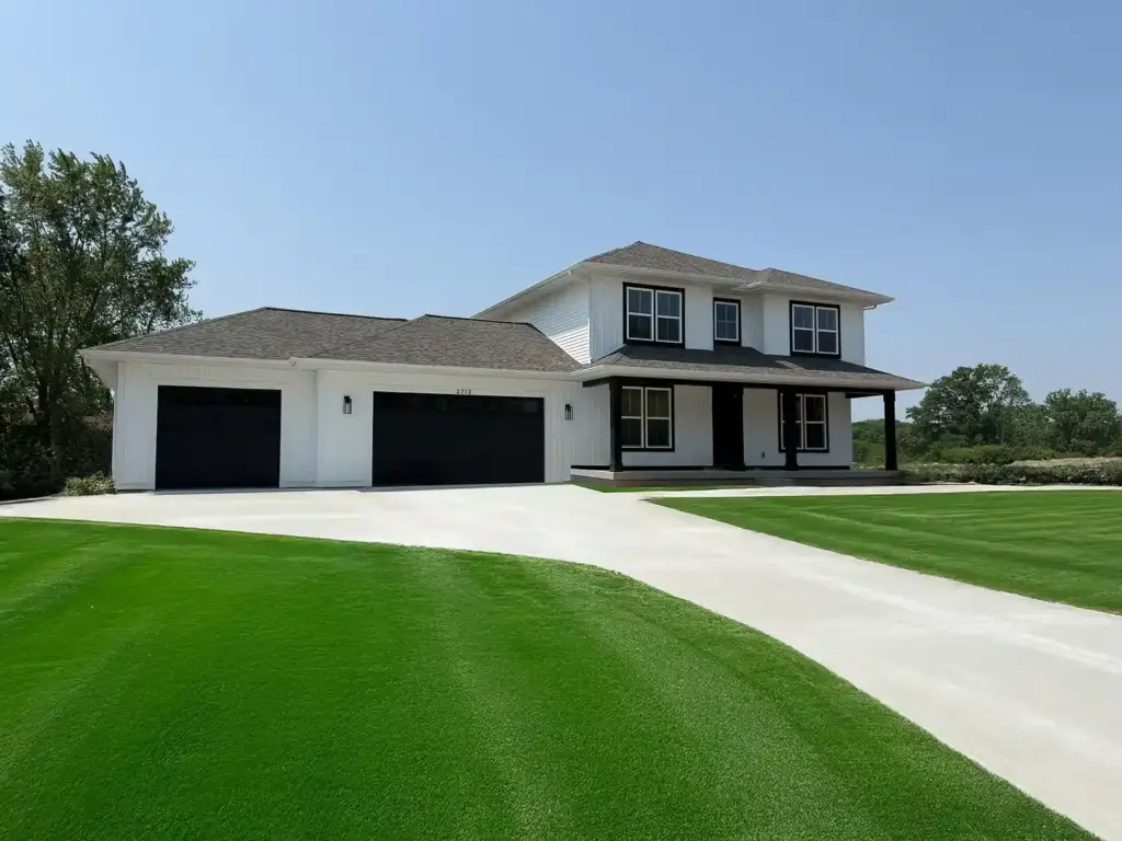 White and black two-story custom home with three-car garage and covered porch