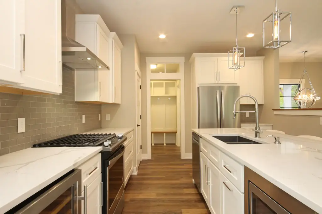 Custom home kitchen with white cabinets, quartz island, and stainless appliances