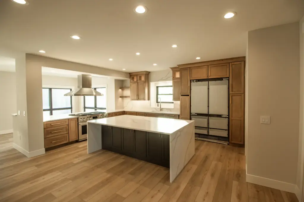 Renovated kitchen with wood cabinets, dark island, and waterfall stone countertop