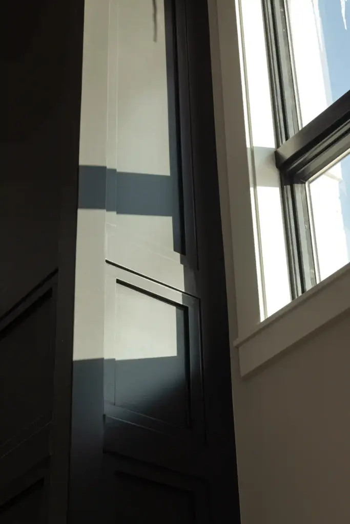 Dark wall paneling beside tall windows in a renovated interior