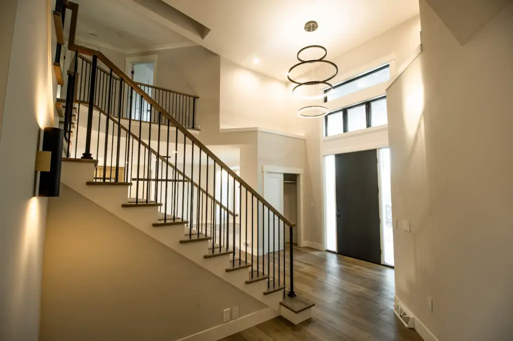 Renovated entry with modern staircase, black railings, and ring chandelier