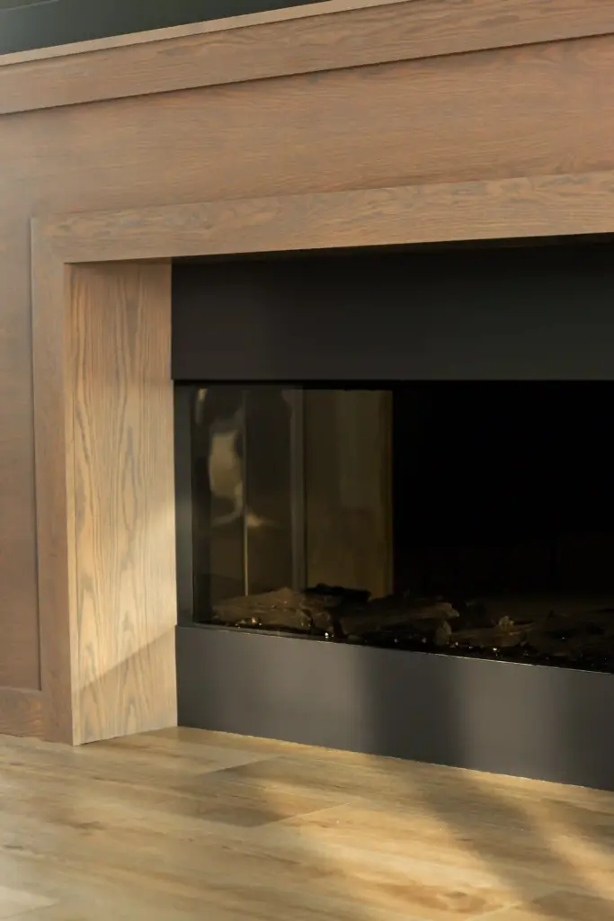 Wood fireplace surround with black firebox in a renovated West Michigan interior