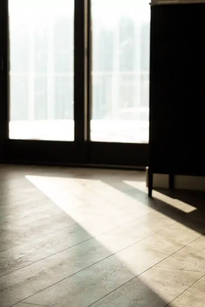Sunlight across wood-look flooring beside glass doors in a renovated interior