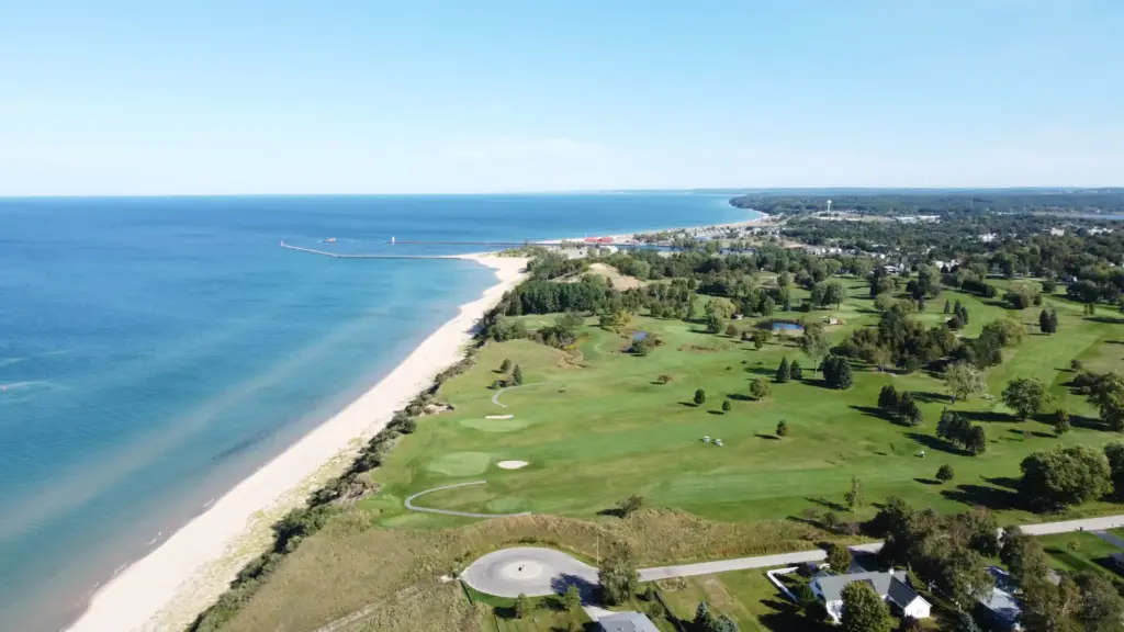 Aerial view of West Michigan lakeshore with beach, golf course, and Lake Michigan.