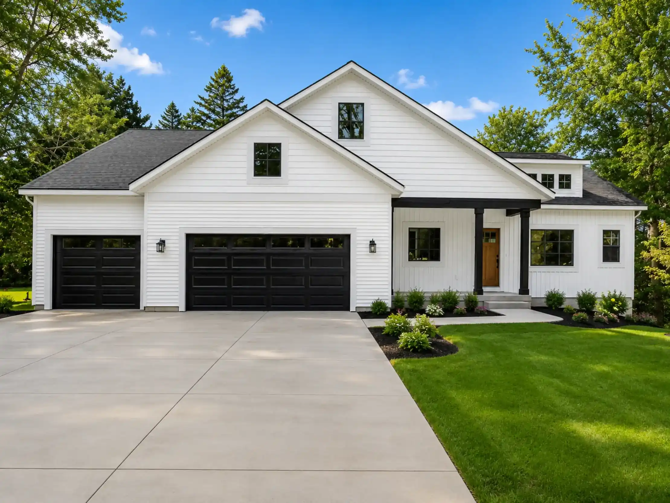 White custom home with black garage doors, covered front porch, landscaped lawn, and concrete driveway
